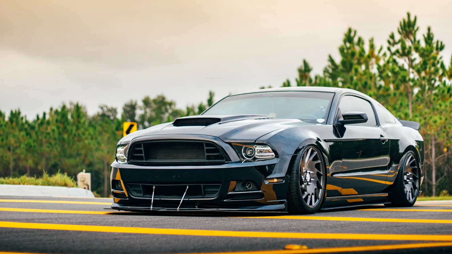 Slammed black Ford Mustang with front splitter on a highway