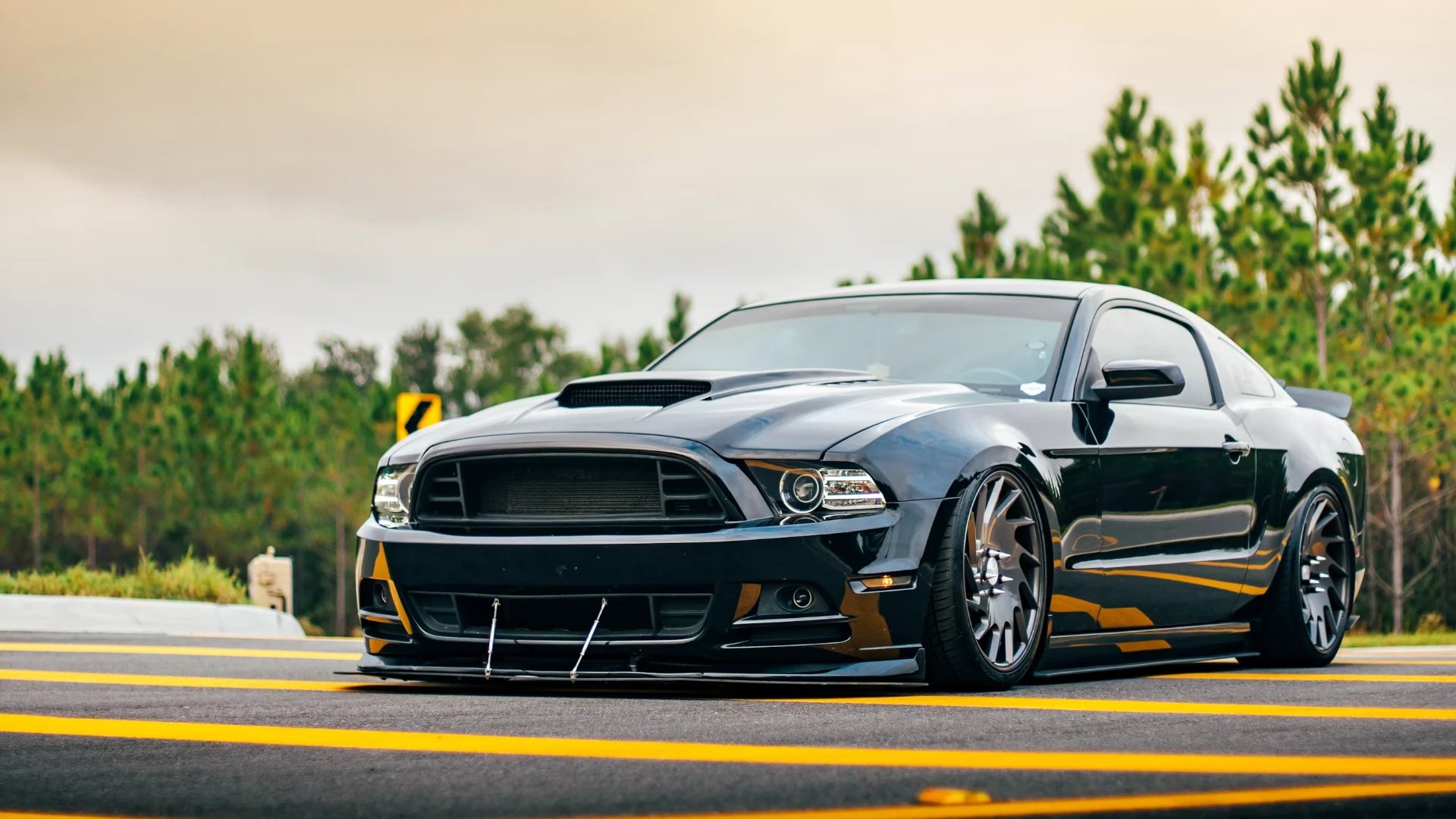 Slammed black Ford Mustang with front splitter on a highway